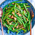 Green Beans with Caramelized Onions & Cashews is the perfect #vegan side dish for #Thanksgiving or any night of the week. It's super simple to make and tastes fresh. Add something lighter to your #holiday feast!
