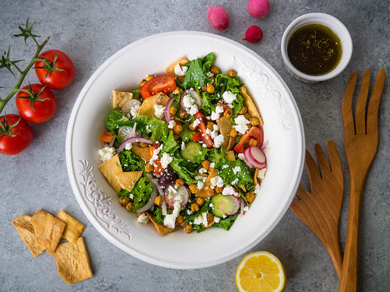 mustard greens greek salad in white bowl
