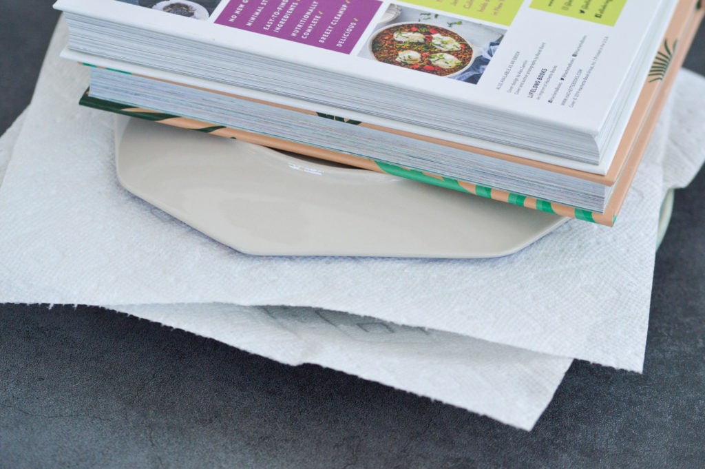 tofu pressed between two plates with a book on top